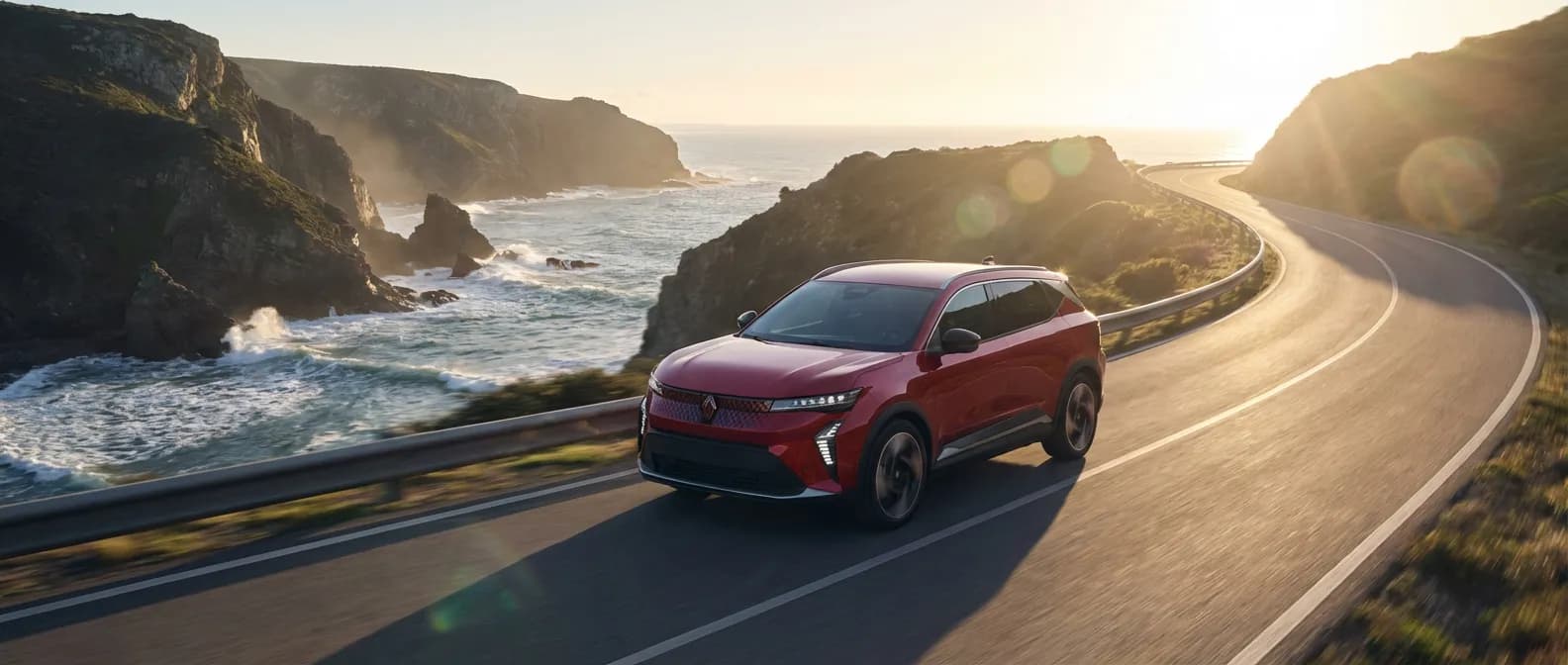 Le nouveau Renault Scenic 5 électrique sur une route côtière au lever du soleil