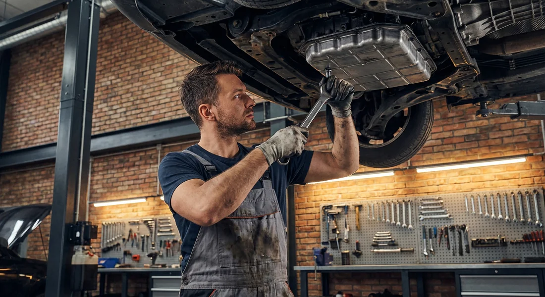 Mécanicien effectuant la vidange d'une boîte de vitesses automatique sur une Peugeot.